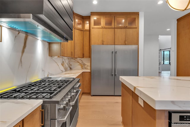4627 Cimarron Dr, Bloomfield Hills, MI 48302 - kitchen with high end appliances, wall chimney exhaust hood, light wood-style flooring, brown cabinets, and recessed lighting