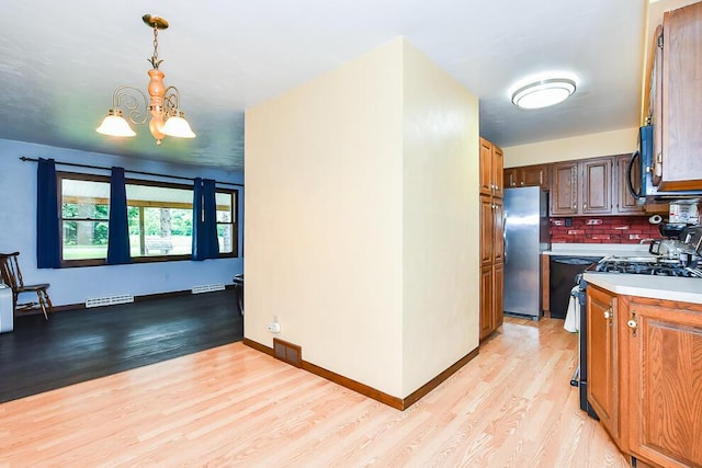 12345 Beadle Lake Rd, Battle Creek, MI 49014 - kitchen featuring black appliances, light wood-style flooring, a chandelier, light countertops, and tasteful backsplash
