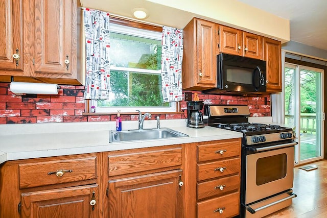 12345 Beadle Lake Rd, Battle Creek, MI 49014 - kitchen featuring stainless steel gas range oven, black microwave, light countertops, brown cabinetry, and tasteful backsplash