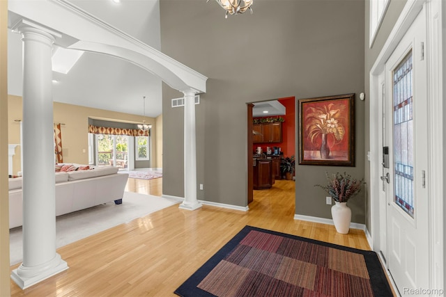 24065 Timber Creek Ln, Flat Rock, MI 48134 - entryway featuring ornate columns, light wood-style floors, a towering ceiling, and a chandelier