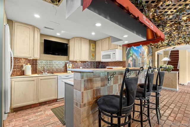 24065 Timber Creek Ln, Flat Rock, MI 48134 - kitchen featuring white appliances, brick floors, a kitchen bar, decorative backsplash, and light countertops
