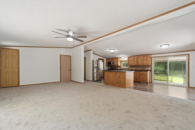 19905 N Ave, Battle Creek, MI 49017 - kitchen with stainless steel appliances, open floor plan, light carpet, vaulted ceiling, and brown cabinetry
