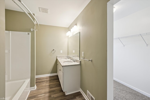 180 Ash St, Corunna, MI 48817 - bathroom featuring vanity, tub / shower combination, wood finished floors, and a walk in closet