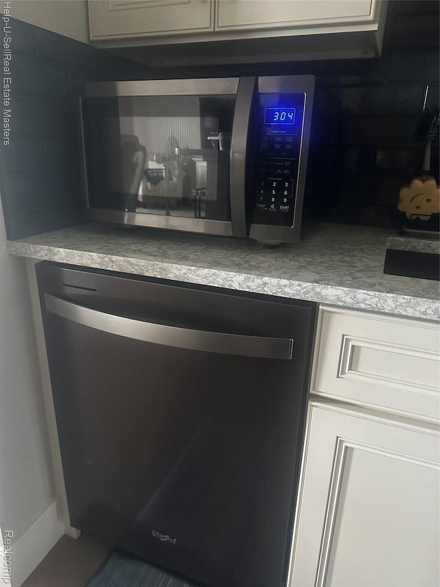 1975 Michigan Ave Unit 47, Marysville, MI 48040 - kitchen view of dishwashing machine, stainless steel microwave, light countertops, and decorative backsplash
