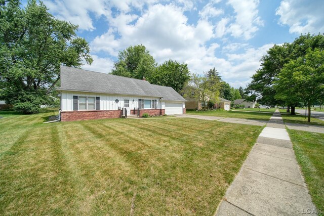 608 Brook St, Tecumseh, MI 49286 - view of front of property with brick siding, an attached garage, a front lawn, driveway, and board and batten siding