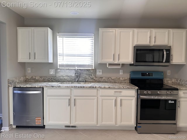 820 Woodhaven Dr, Commerce Twp, MI 48390 - kitchen featuring stainless steel appliances, white cabinets, light stone countertops, and light tile patterned floors