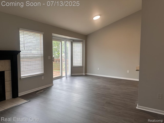 820 Woodhaven Dr, Commerce Twp, MI 48390 - unfurnished living room featuring dark wood-style flooring, a tile fireplace, and vaulted ceiling