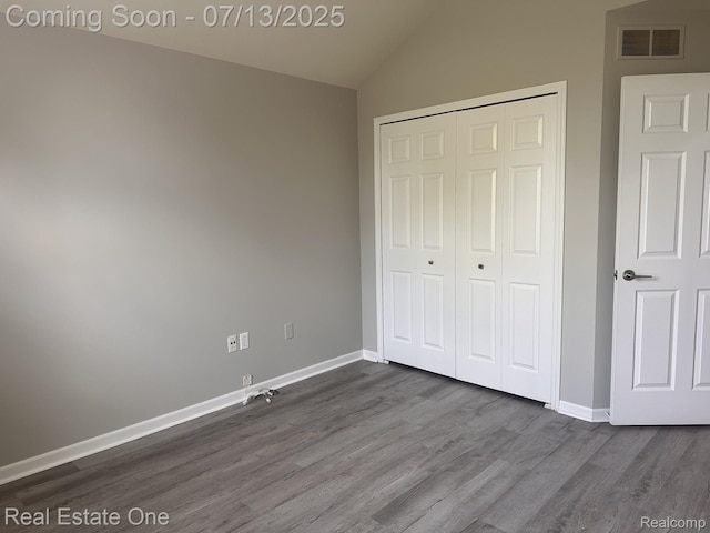 820 Woodhaven Dr, Commerce Twp, MI 48390 - unfurnished bedroom with vaulted ceiling, dark wood-type flooring, and a closet