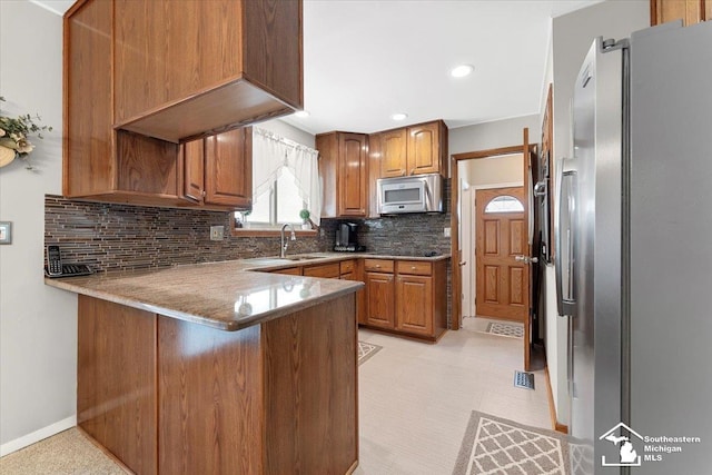 15930 Drysdale St, Southgate, MI 48195 - kitchen featuring appliances with stainless steel finishes, a peninsula, brown cabinetry, decorative backsplash, and recessed lighting