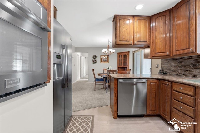 15930 Drysdale St, Southgate, MI 48195 - kitchen featuring appliances with stainless steel finishes, brown cabinetry, decorative backsplash, a chandelier, and a peninsula