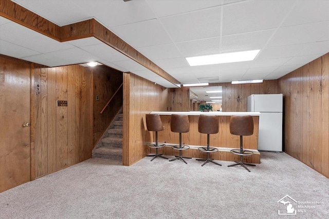 15930 Drysdale St, Southgate, MI 48195 - kitchen with freestanding refrigerator, wood walls, carpet floors, and a breakfast bar