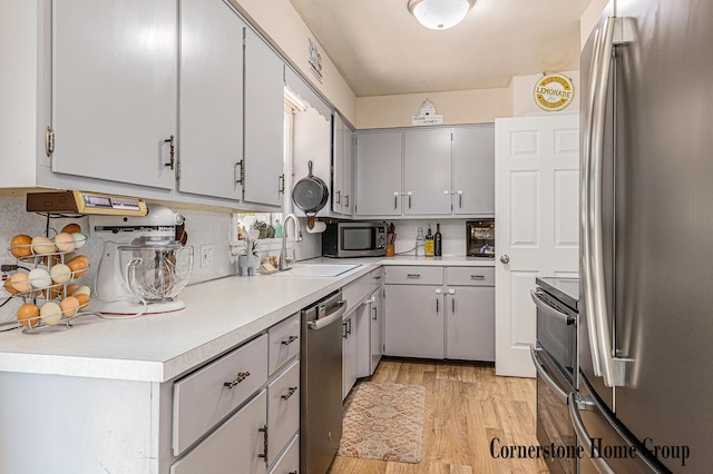 8611 Byron Center Ave SW, Byron Center, MI 49315 - kitchen featuring appliances with stainless steel finishes, tasteful backsplash, light wood-style floors, light countertops, and gray cabinets