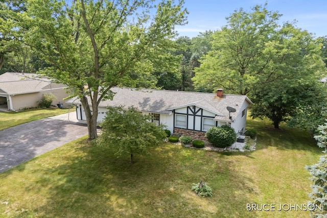 1236 S Van Bruggen Dr, Plainwell, MI 49080 - tudor-style house with concrete driveway, a front yard, stone siding, and a chimney