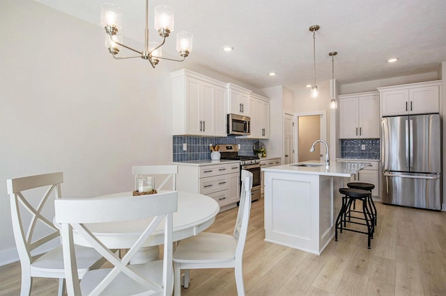 4818 Hidden River Ave SW Unit 51, Wyoming, MI 49418 - kitchen featuring appliances with stainless steel finishes, a breakfast bar, decorative backsplash, a chandelier, and light wood-style flooring