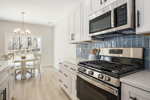4818 Hidden River Ave SW Unit 51, Wyoming, MI 49418 - kitchen featuring stainless steel appliances, a chandelier, backsplash, light countertops, and light wood-type flooring