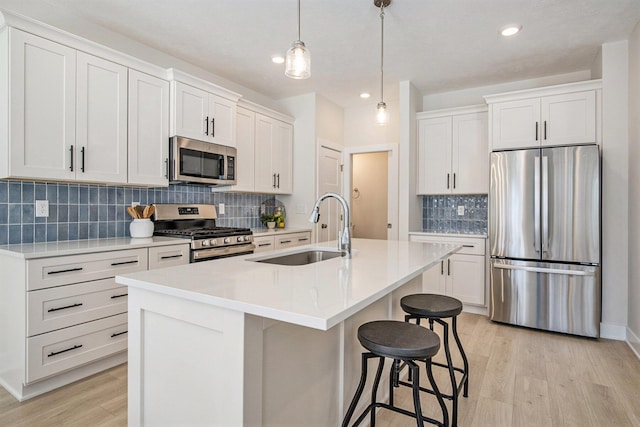 4818 Hidden River Ave SW Unit 51, Wyoming, MI 49418 - kitchen featuring appliances with stainless steel finishes, light wood-style flooring, tasteful backsplash, a breakfast bar area, and an island with sink