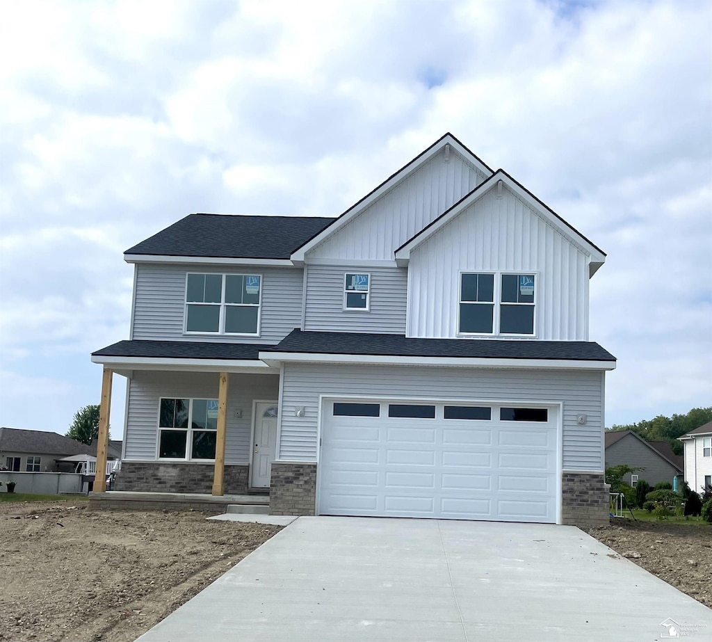 7823 Audubon Ln, Newport, MI 48166 - view of front of home with a porch, driveway, an attached garage, board and batten siding, and brick siding
