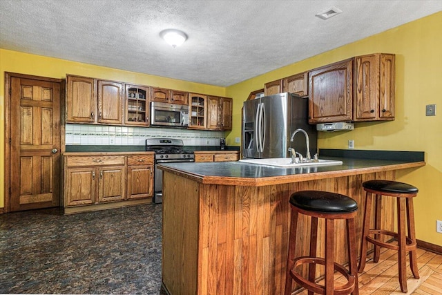 16253 1st Ln, Union Pier, MI 49129 - kitchen featuring stainless steel appliances, dark countertops, a kitchen bar, a peninsula, and a textured ceiling