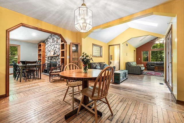 16253 1st Ln, Union Pier, MI 49129 - dining space featuring hardwood / wood-style floors, a stone fireplace, vaulted ceiling, and a chandelier
