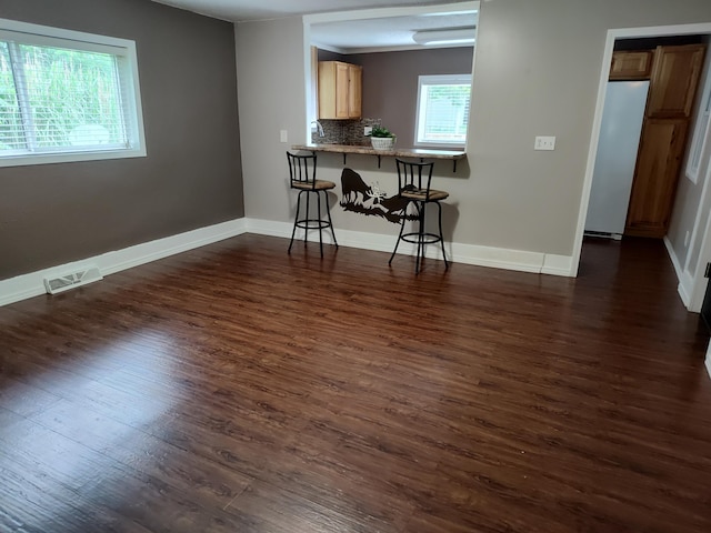 411 Block Rd, Coldwater, MI 49036 - kitchen featuring freestanding refrigerator, dark wood-type flooring, a breakfast bar, and decorative backsplash