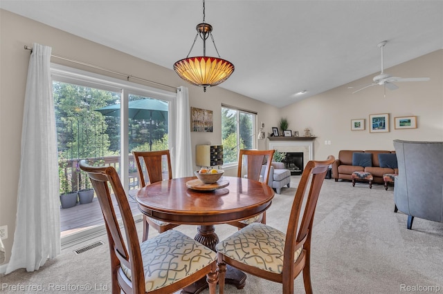77 Sedum, Howell, MI 48843 - dining space featuring light colored carpet, lofted ceiling, a glass covered fireplace, and a ceiling fan