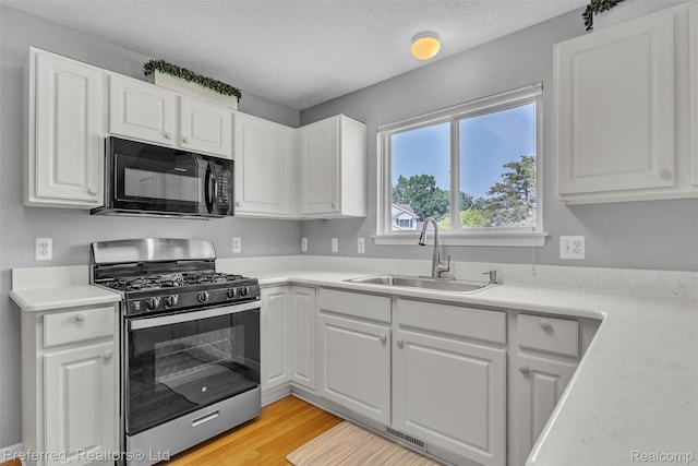 77 Sedum, Howell, MI 48843 - kitchen featuring stainless steel gas range oven, black microwave, white cabinetry, light countertops, and light wood-style flooring