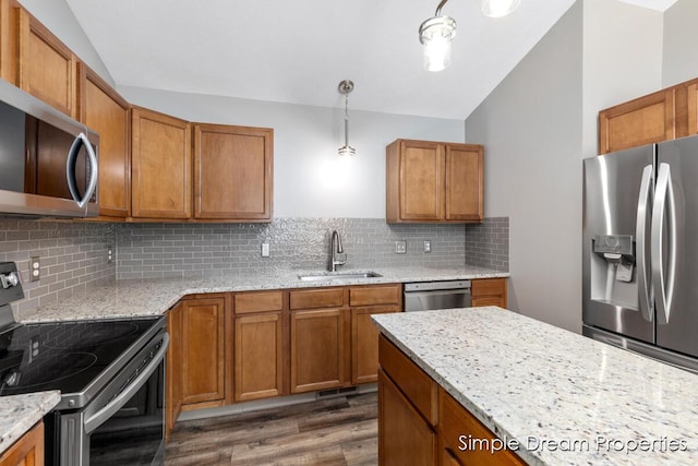 1026 Coldbrook St NE, Grand Rapids, MI 49503 - kitchen with stainless steel appliances, lofted ceiling, brown cabinetry, dark wood-style floors, and light stone countertops