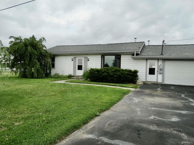 1570 Evon Rd, Saginaw, MI 48601 - ranch-style house featuring an attached garage, asphalt driveway, a front lawn, and roof with shingles