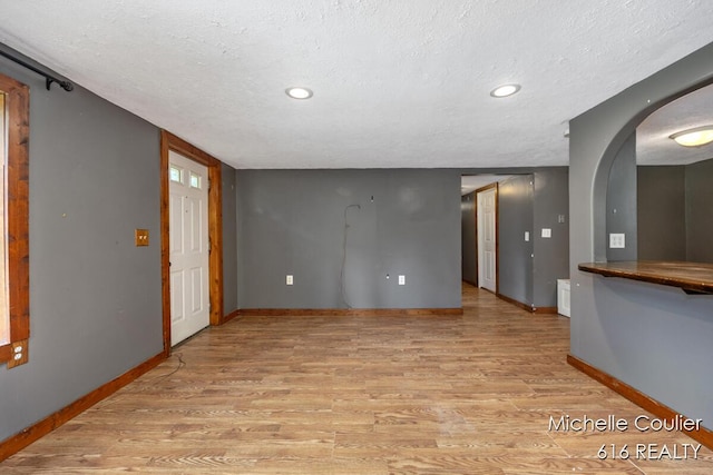 9583 E 5 Mile Rd, Big Rapids, MI 49307 - empty room with light wood-style flooring, arched walkways, a textured ceiling, and recessed lighting