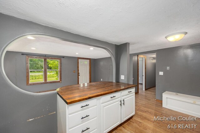 9583 E 5 Mile Rd, Big Rapids, MI 49307 - kitchen featuring wood counters, light wood-style flooring, arched walkways, a textured ceiling, and white cabinets