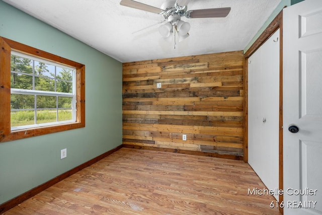 9583 E 5 Mile Rd, Big Rapids, MI 49307 - spare room featuring light wood-style flooring, wood walls, ceiling fan, and a textured ceiling