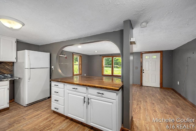 9583 E 5 Mile Rd, Big Rapids, MI 49307 - kitchen featuring freestanding refrigerator, arched walkways, light wood finished floors, white cabinetry, and a textured ceiling