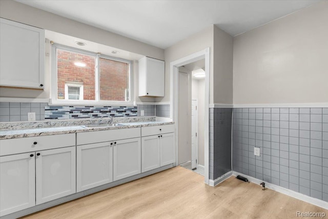11110 Wayburn St, Grosse Pointe, MI 48224 - kitchen with light wood-type flooring, tile walls, white cabinets, wainscoting, and light stone countertops