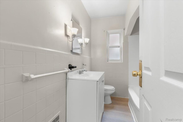 11110 Wayburn St, Grosse Pointe, MI 48224 - bathroom featuring tile walls, vanity, wood finished floors, and a wainscoted wall