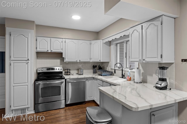 972 Goodale Ave, Clawson, MI 48017 - kitchen with appliances with stainless steel finishes, white cabinets, light stone countertops, a peninsula, and dark wood-style floors