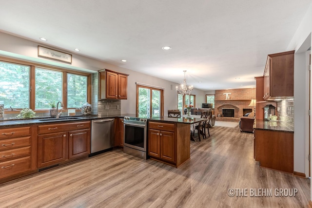 6340 Cannon Highlands Dr NE, Belmont, MI 49306 - kitchen with stainless steel appliances, open floor plan, a peninsula, brown cabinets, and a chandelier