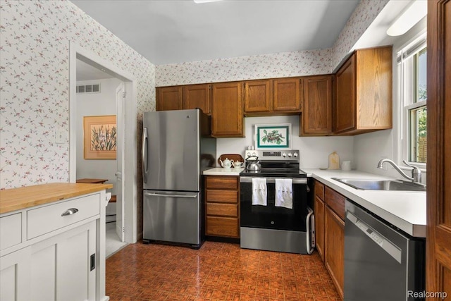15588 Kirkshire Ave, Beverly Hills, MI 48025 - kitchen featuring stainless steel appliances, wallpapered walls, light countertops, and brown cabinets