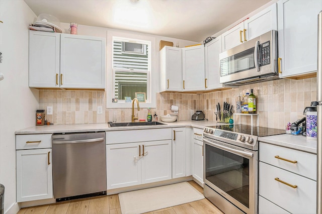 1213 Prospect Ave SE, Grand Rapids, MI 49507 - kitchen with stainless steel appliances, light countertops, light wood-style flooring, and white cabinets