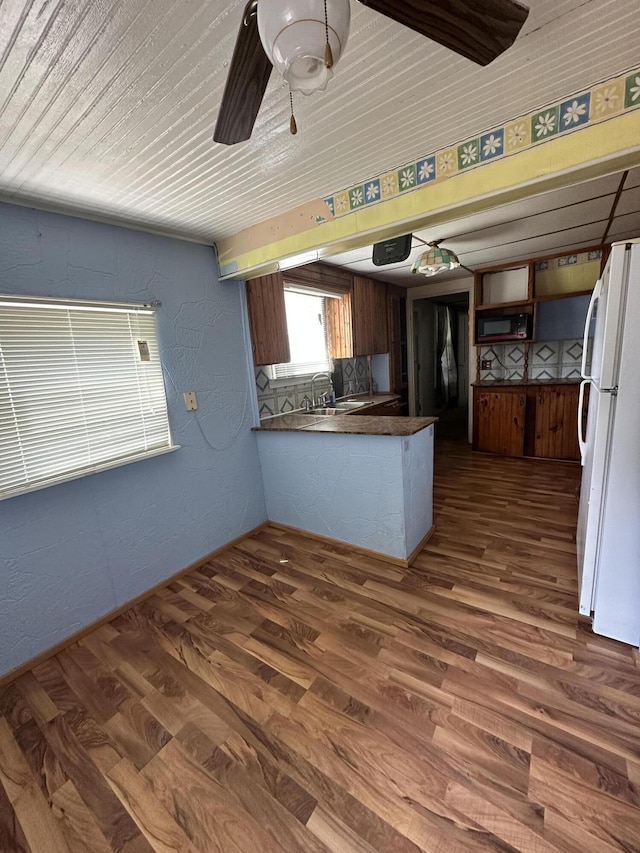 811 W Lincoln Ave, Ionia, MI 48846 - kitchen featuring freestanding refrigerator, black microwave, a peninsula, dark wood-style floors, and dark countertops