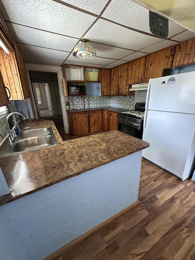 811 W Lincoln Ave, Ionia, MI 48846 - kitchen with freestanding refrigerator, stainless steel range with gas stovetop, brown cabinets, a drop ceiling, and a peninsula