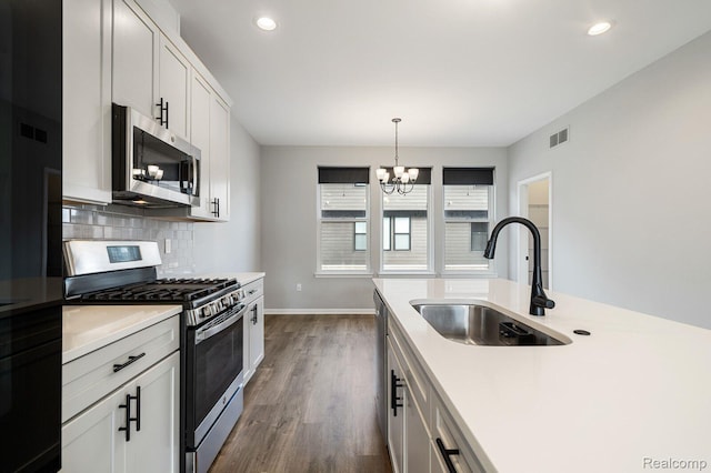 1087 Hampton Cir Unit 55, Detroit, MI 48207 - kitchen with appliances with stainless steel finishes, a chandelier, dark wood-style flooring, light countertops, and decorative backsplash