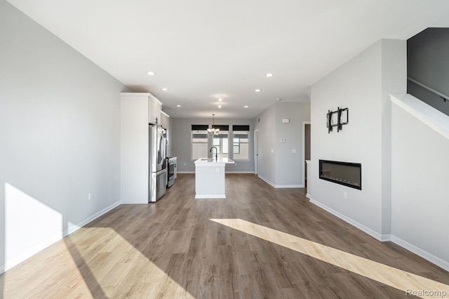1087 Hampton Cir Unit 55, Detroit, MI 48207 - unfurnished living room featuring a chandelier, a glass covered fireplace, wood finished floors, and recessed lighting