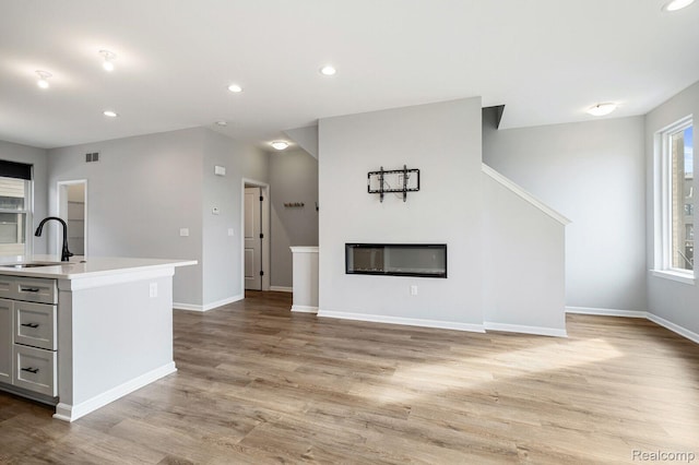 1087 Hampton Cir Unit 55, Detroit, MI 48207 - unfurnished living room featuring light wood finished floors, recessed lighting, and a glass covered fireplace