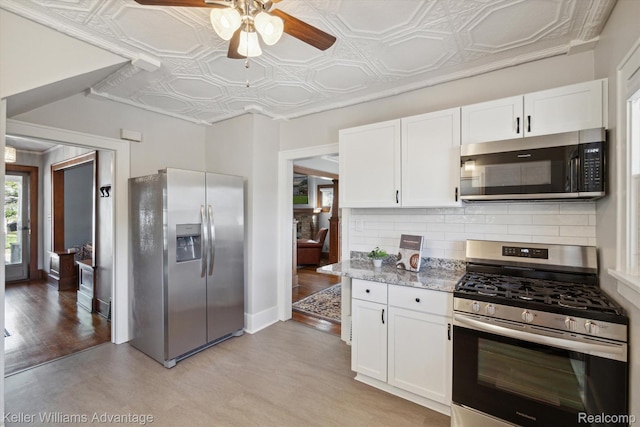 402 E 7th St, Royal Oak, MI 48067 - kitchen with appliances with stainless steel finishes, ceiling fan, decorative backsplash, white cabinetry, and an ornate ceiling