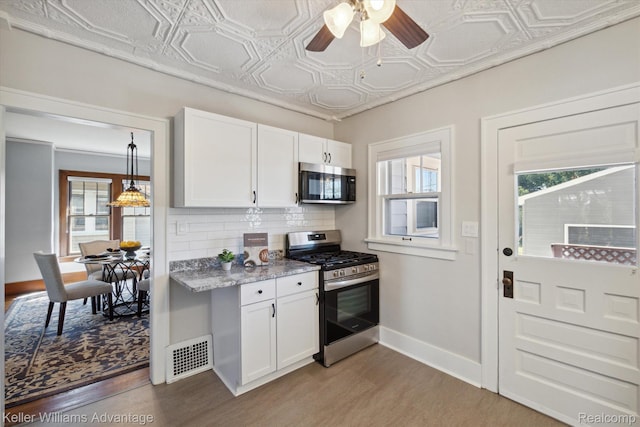 402 E 7th St, Royal Oak, MI 48067 - kitchen featuring an ornate ceiling, appliances with stainless steel finishes, light wood-style floors, backsplash, and white cabinets