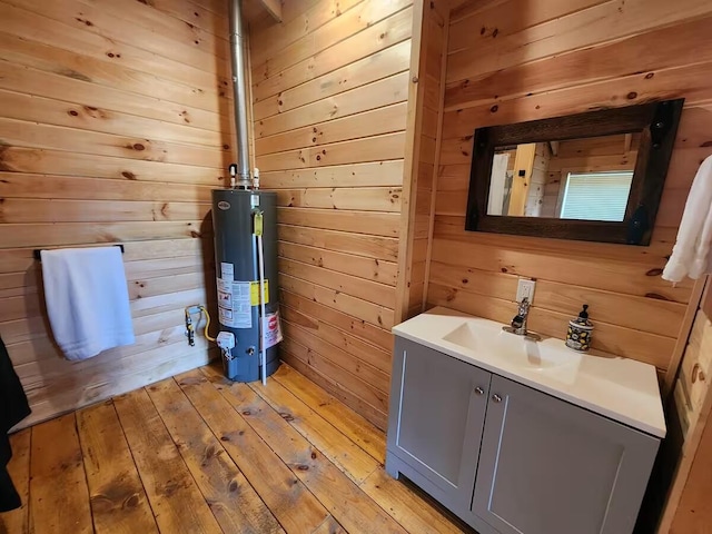2599 N Pine Ave, White Cloud, MI 49349 - bathroom featuring gas water heater, vanity, wood walls, and wood-type flooring