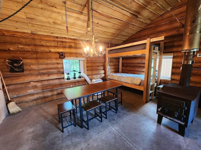 2599 N Pine Ave, White Cloud, MI 49349 - dining room featuring concrete floors, lofted ceiling, a wood stove, a chandelier, and rustic walls