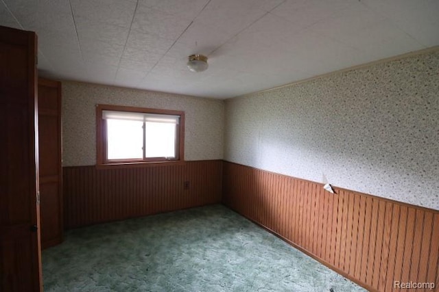 6048 N Lapeer Rd, Fostoria, MI 48435 - unfurnished room with a wainscoted wall, carpet, wallpapered walls, and wood walls