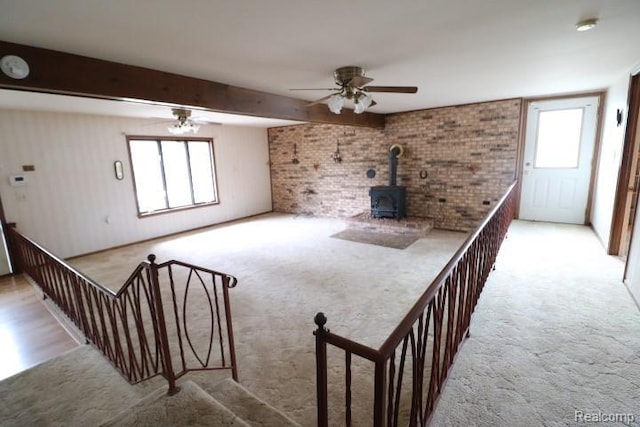6048 N Lapeer Rd, Fostoria, MI 48435 - unfurnished living room featuring healthy amount of natural light, carpet, ceiling fan, beam ceiling, and brick wall