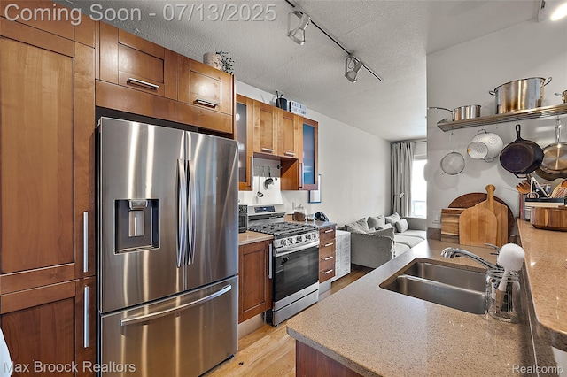 432 S Washington Ave Unit 1402, Royal Oak, MI 48067 - kitchen with appliances with stainless steel finishes, light wood-style floors, a textured ceiling, brown cabinetry, and light countertops